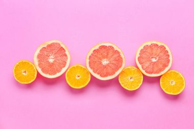 Pembe arka planda taze portakal ve greyfurt dilimleri.