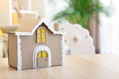 Tahta masadaki el yapımı karton ev.