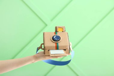 Renkli arka planda karton fotoğraf makinesi olan kadın el.