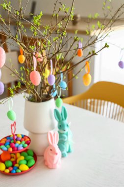 Yemek masasındaki vazoda paskalya yumurtalarıyla süslenmiş ağaç dalları.