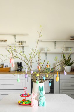 Mutfaktaki yemek masasında Paskalya yumurtası ve dekorun yanında dur.