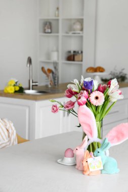 Güzel çiçekler, Paskalya yumurtası, tavşanlar ve yemek masasında tebrik kartı.