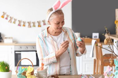 Evde paskalya yumurtası boyayan olgun bir kadın.