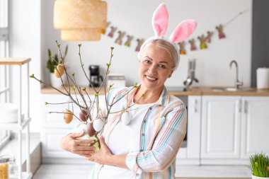 Evde tavşan kulaklı ve paskalya desenli olgun bir kadın.