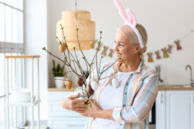 Evde tavşan kulaklı ve paskalya desenli olgun bir kadın.