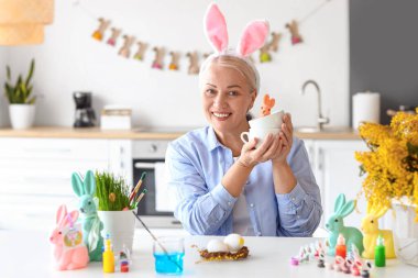 Evde tavşan kulaklı ve paskalya desenli olgun bir kadın.