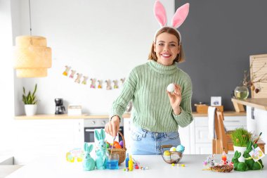 Güzel bir kadın evde paskalya yumurtası boyuyor.