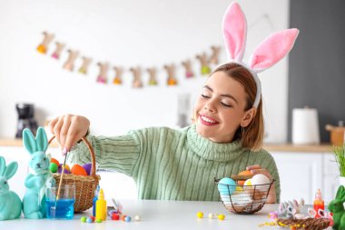 Güzel bir kadın evde paskalya yumurtası boyuyor.