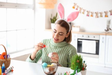 Güzel bir kadın evde paskalya yumurtası boyuyor.