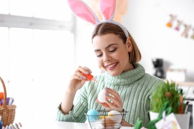 Güzel bir kadın evde paskalya yumurtası boyuyor.