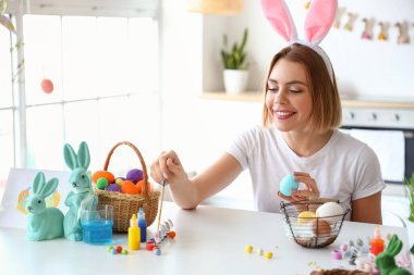 Güzel bir kadın evde paskalya yumurtası boyuyor.
