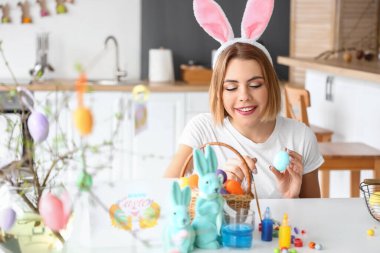 Güzel bir kadın evde paskalya yumurtası boyuyor.