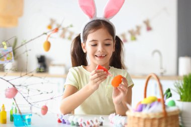 Komik küçük kız evde paskalya yumurtası boyuyor.