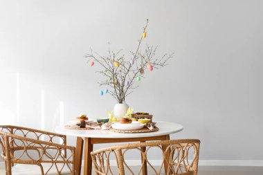 Paskalya yumurtalarıyla süslenmiş ağaç dalları yemek masasında servis ediliyor.