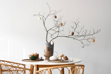 Ağaç dallarıyla yemek masası ve vazoda Paskalya yumurtası.