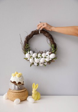 Gri duvara el yapımı Paskalya çelengi asan kadın.