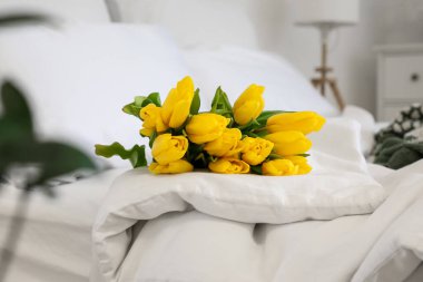 Sarı laleler yatağın üzerinde, aydınlık odada, yakın plan