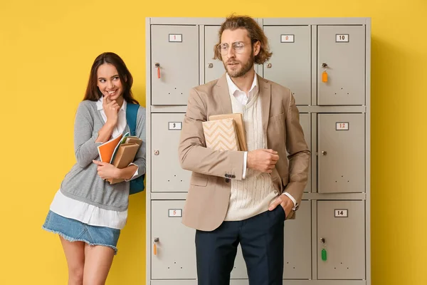 Female Student Looking Her Teacher While Standing Locker Yellow Background — Stock Photo, Image
