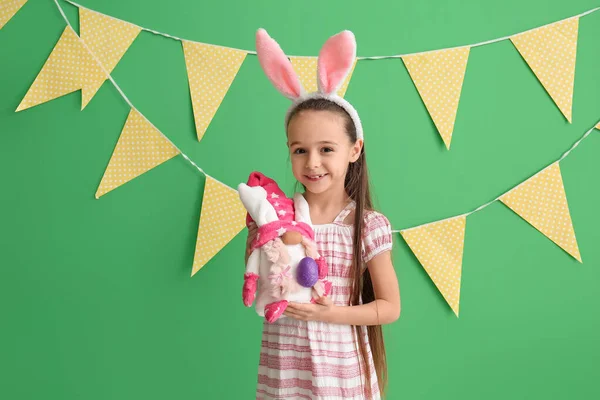 小兔子耳朵的小女孩拿着绿色背景的复活节彩蛋玩具 — 图库照片