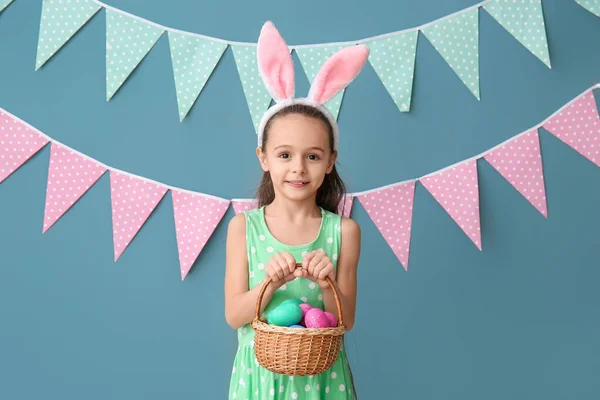 Kleines Mädchen Mit Hasenohren Und Korb Mit Ostereiern Auf Blauem — Stockfoto