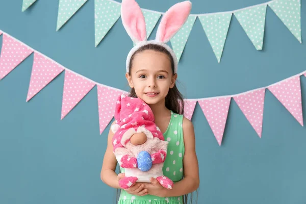 小兔子耳朵的小女孩拿着蓝色背景的复活节彩蛋玩具 — 图库照片