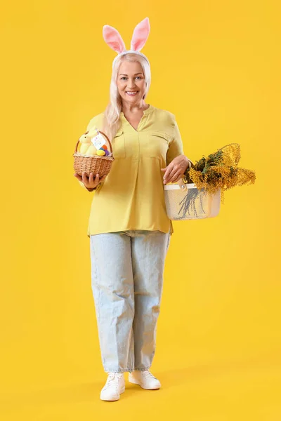 Rijpe Vrouw Met Konijnenoren Paasmand Bloemen Gele Achtergrond — Stockfoto