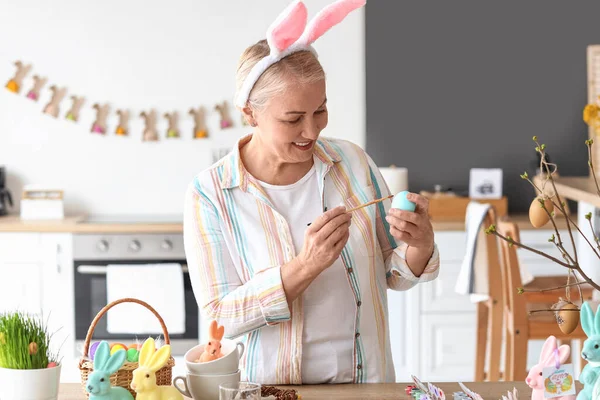 Evde paskalya yumurtası boyayan olgun bir kadın.
