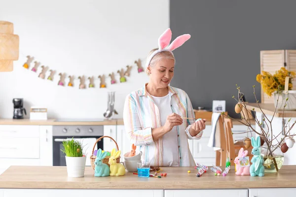 Evde paskalya yumurtası boyayan olgun bir kadın.
