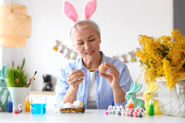 Rijpere Vrouw Schilderen Paaseieren Thuis — Stockfoto