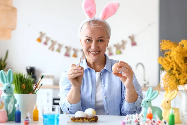 Evde paskalya yumurtası boyayan olgun bir kadın.