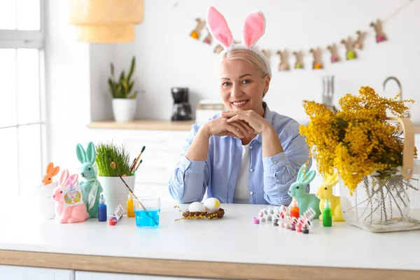 Evde paskalya yumurtası boyayan olgun bir kadın.