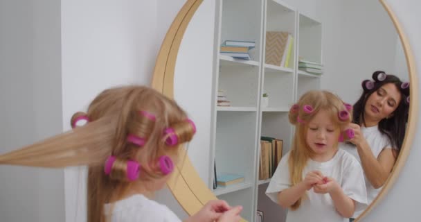 女人在镜子前卷曲着小女儿的头发 — 图库视频影像