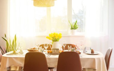 Pencerenin yanındaki Paskalya kutlaması için masa hazırlanmış aydınlık odanın içinde.