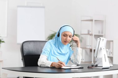 Ofiste çalışan kulaklıklı Müslüman sekreter.