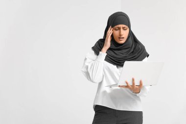 Hafif arka planda dizüstü bilgisayarı olan stresli Müslüman sekreter