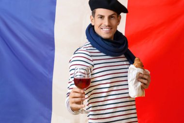 Fransız bayrağına karşı şarap ve kruvasan taşıyan yakışıklı genç adam.