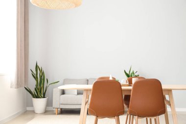 Hafif yemek odasında kahverengi sandalyeli ahşap masa.