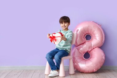 Renkli arka planda hediye ve balon şeklinde sekiz figürlü küçük bir çocuk. Uluslararası Kadınlar Günü kutlamaları