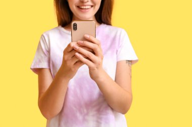 Sarı arka planda cep telefonu kullanan bir kadın, yakın plan. E- posta konsepti