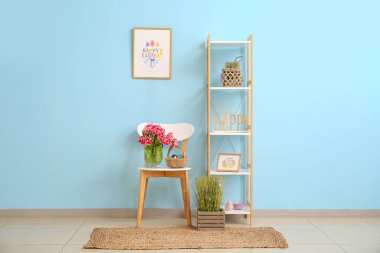 Bir buket lale ve sepette Paskalya yumurtaları sandalyede ve raf odasında renk duvarının yanında.