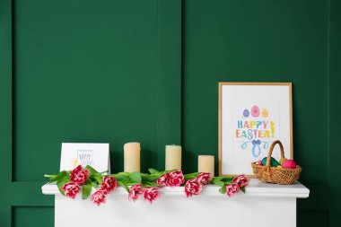 Paskalya yumurtaları, mumlar, resim ve laleler renkli duvarın yanında.