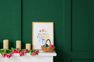 Paskalya yumurtaları, mumlar, resim ve laleler renkli duvarın yanında.