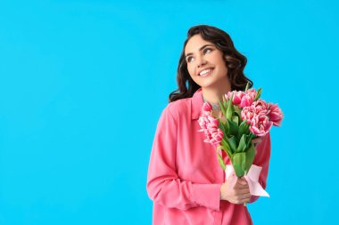Mavi arka planda bir buket lale ile gülümseyen genç kadın. Uluslararası Kadınlar Günü