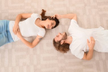 Genç çift evdeki yumuşak halıda yatıyor.
