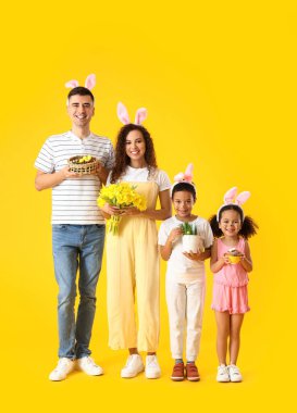 Mutlu aile, Paskalya yumurtaları, laleler, çimenler ve sarı arka planda pasta.