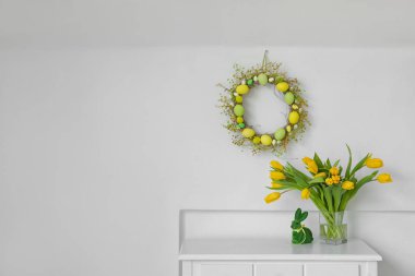 Lale buketi ve tavşanlar ışık duvarının yanında, Paskalya çelengi de odada.