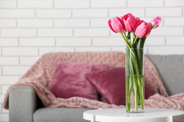 Kanepenin yanındaki masada güzel laleleri olan vazo.