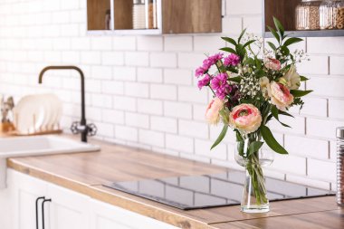 Mutfak tezgahında beyaz tuğla duvarın yanında güzel çiçekler