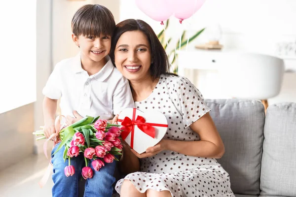 Little son and his mother with gift and bouquet of flowers for International Women\'s day at home