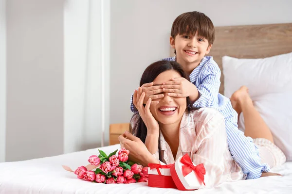 Little son greeting his mother for International Women\'s day in bedroom at home